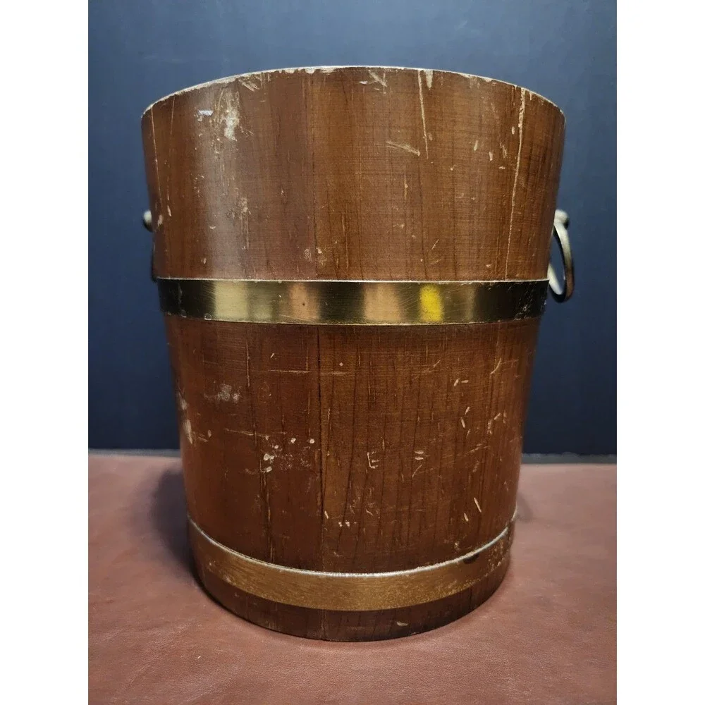 This is a vintage wood and brass barrel-style ice bucket typically measuring...